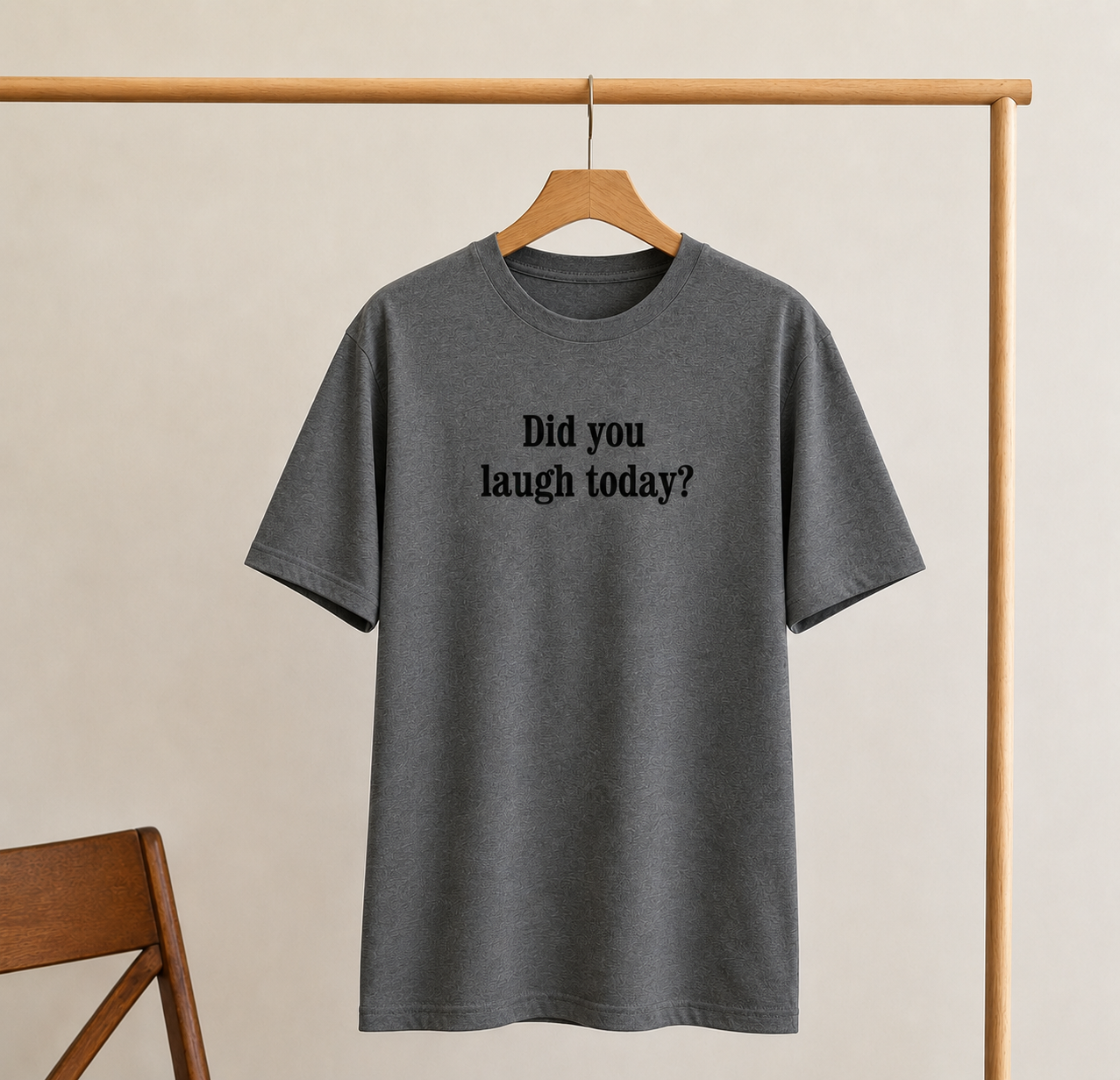 Gray t-shirt with 'Did you laugh today?' text on a wooden hanger against a beige background